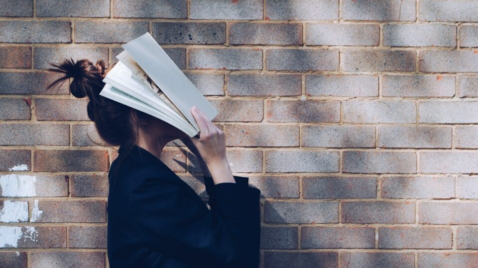 Woman holding a book over her face